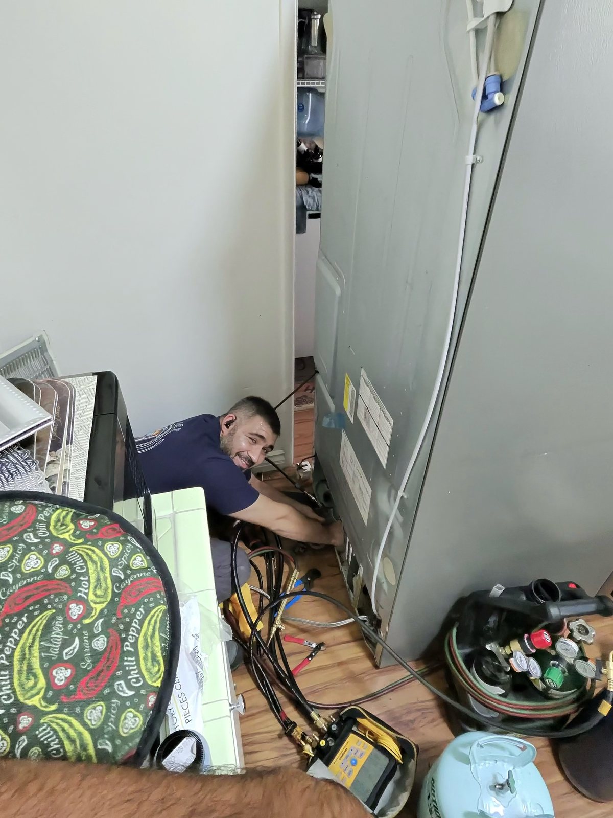 A&Y Appliances technician performing sealed-system refrigerator repair with recovery equipment and gauges