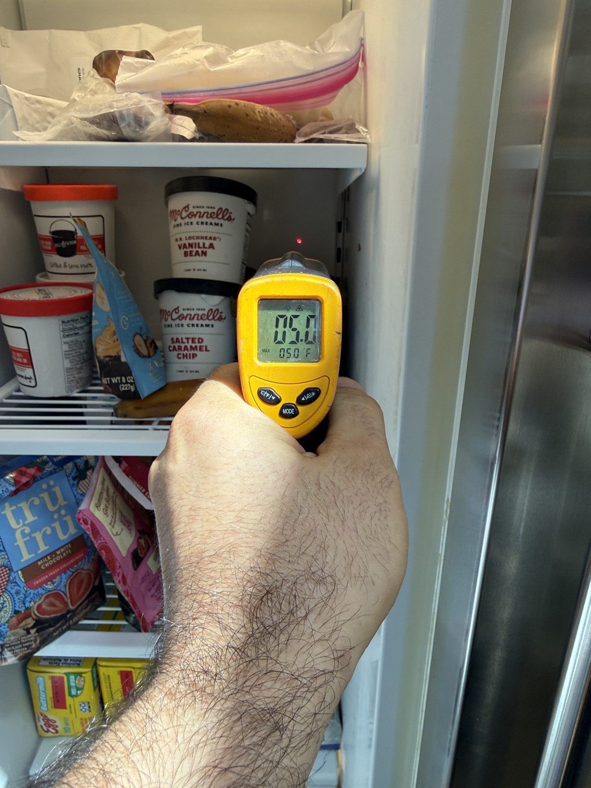 Technician verifying Sub-Zero freezer temperature at 5 degrees Fahrenheit with an infrared thermometer during a performance diagnostic