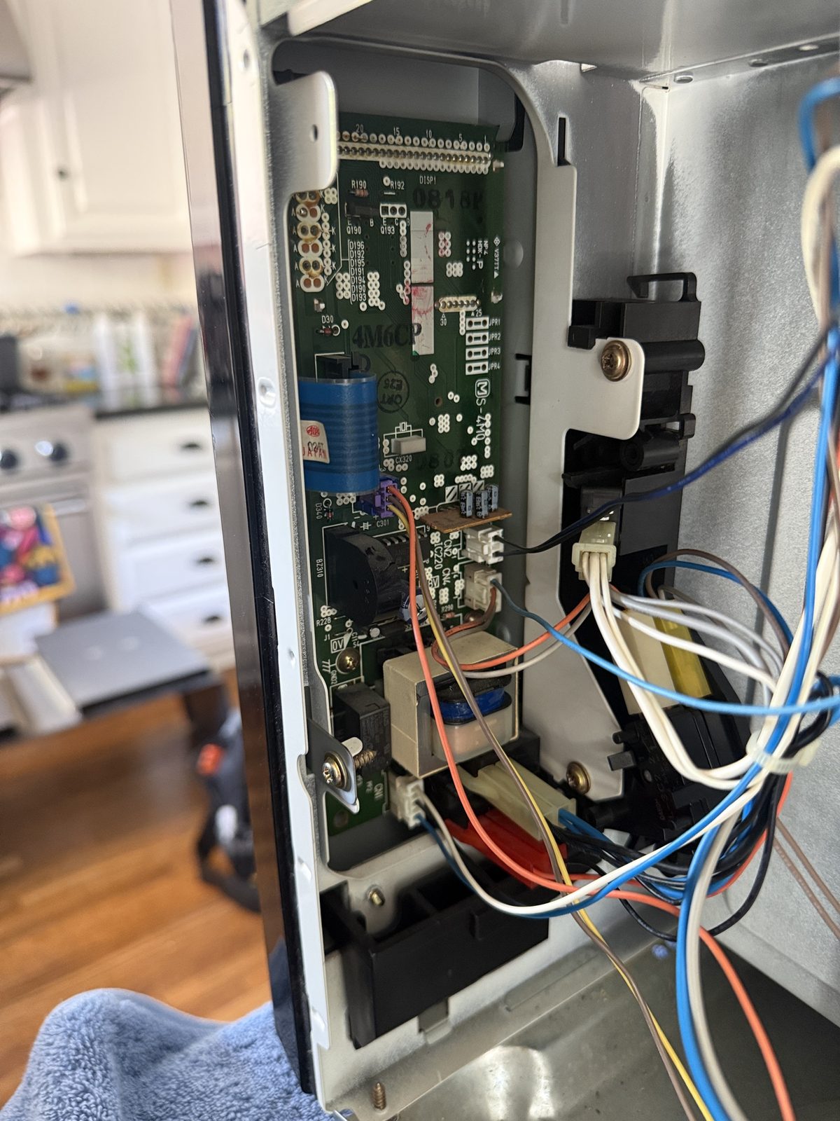 Open control panel of a built-in Thermador microwave showing the control board and door latch housing during in-place repair